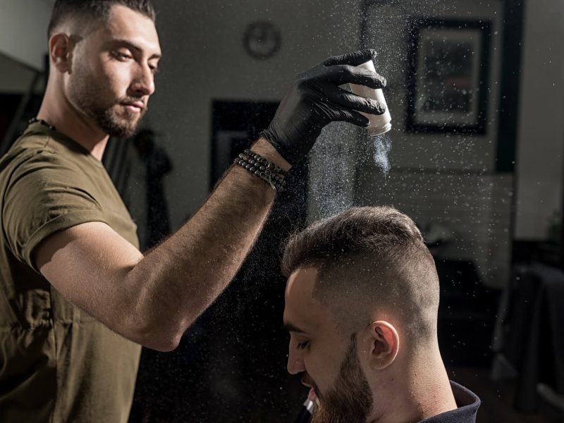 handsome-barber-is-fixing-the-styling-of-brutal-young-man-with-a-dry-styler-at-a-barbershop.jpg
